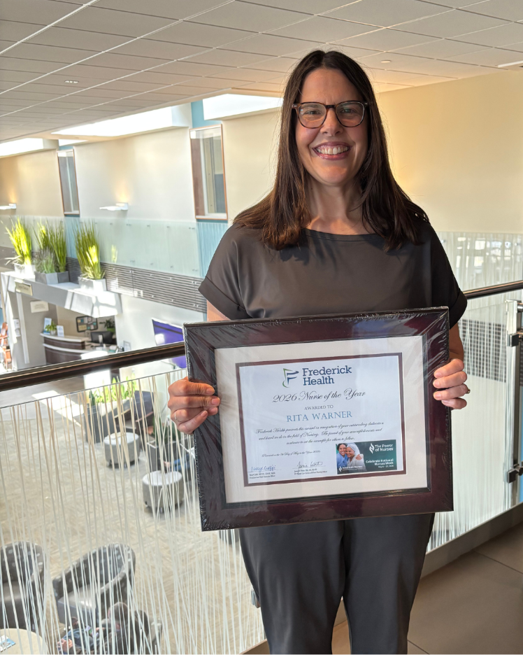 Nurse holds up plaque that reads "Nurse of the Year"