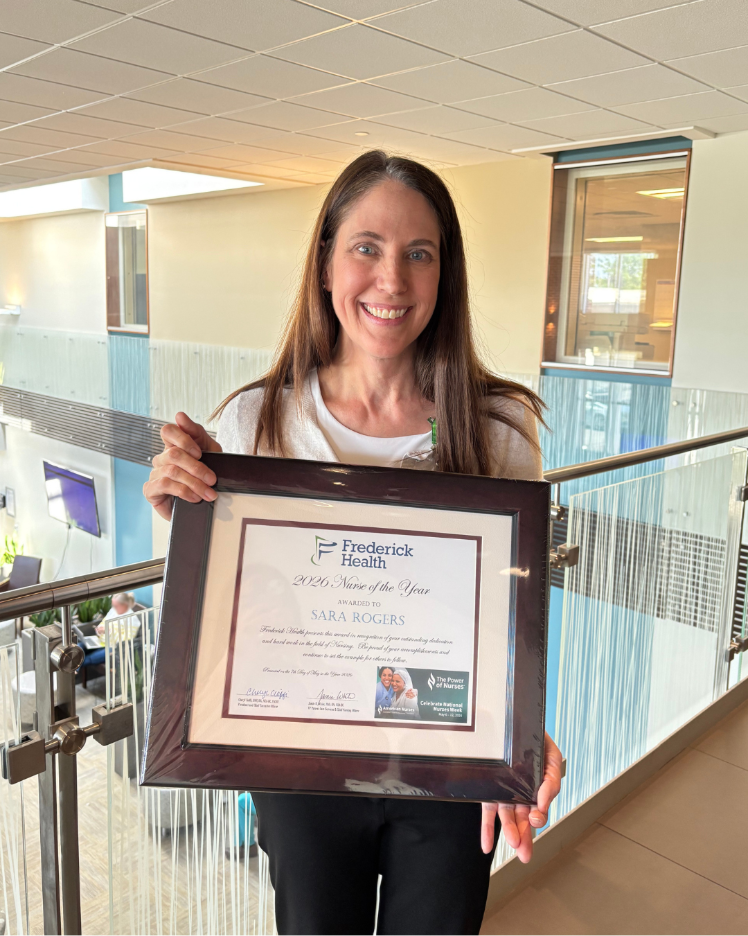Nurse holds up plaque that reads "Nurse of the Year"