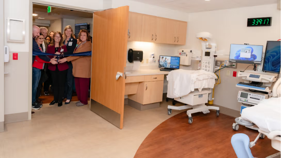 Frederick Health senior leaders gathered to cut ribbon on newly expanded birth place room with new baby incubator and modern finishes