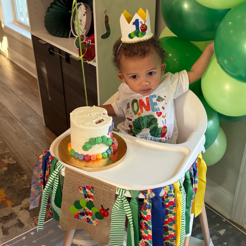 a baby in a high chair eats cake for his first birthday