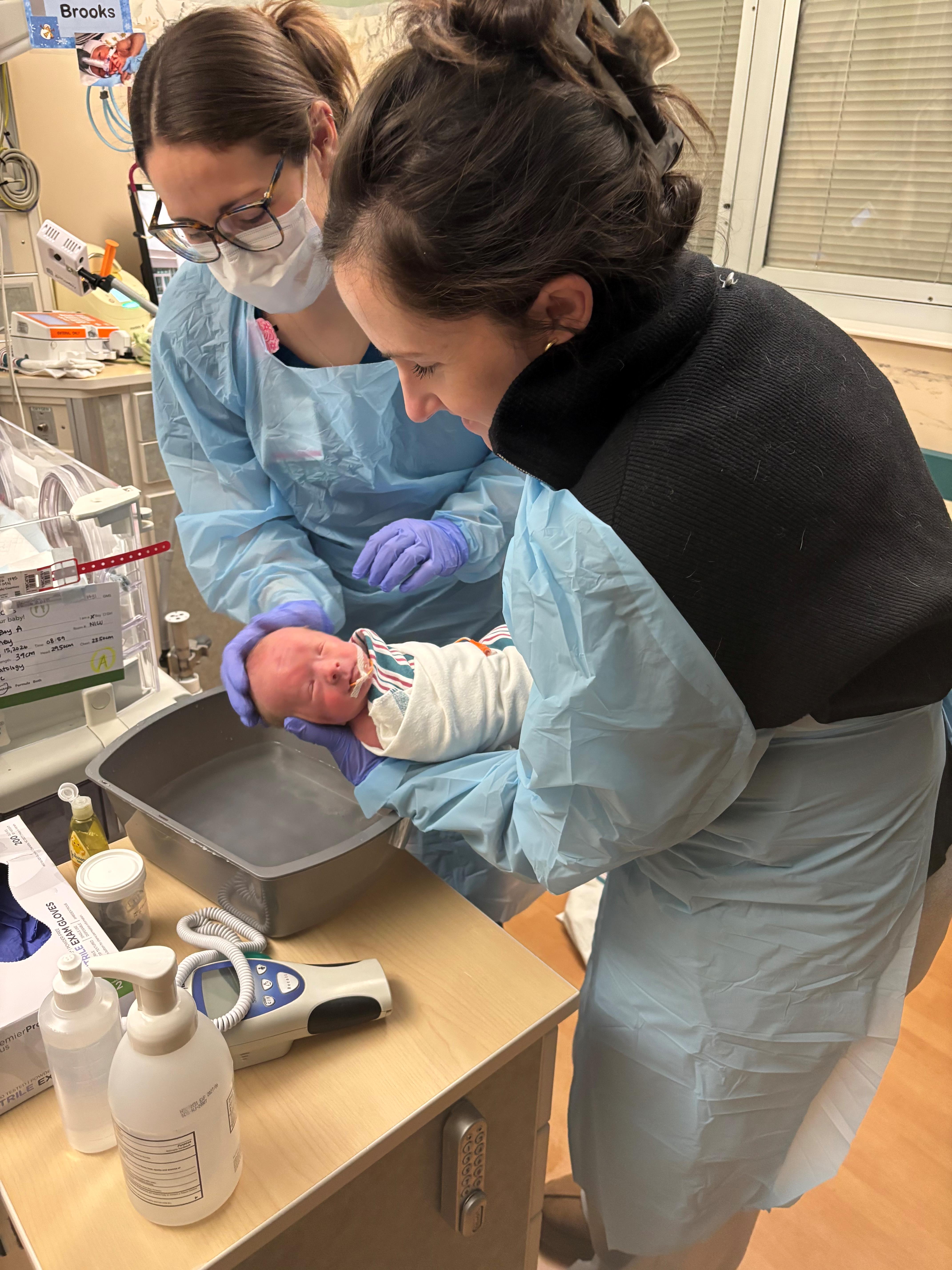 two women bathing a baby in the NICU